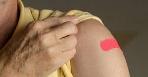 an elderly showing a plaster covering an arm injection vaccination