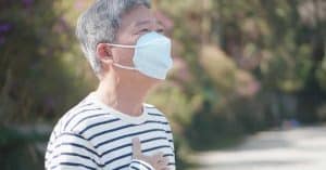 an elderly man wearing mask with hand on chest - respiratory diseases among elderly in singapore